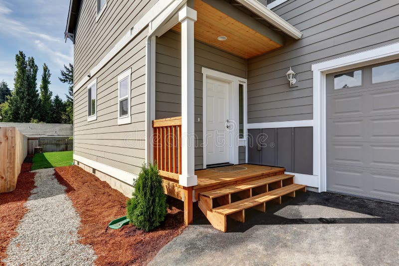 Small front porch with stairs and white entrance door. And gravel walkway to the back yard. Northwest, USA stock image
